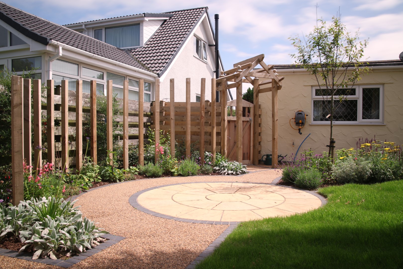 Circular paving and curved timber feature surrounded by flowers and plants